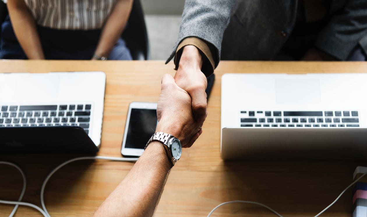real estate agent shaking clients hand over a real estate contract