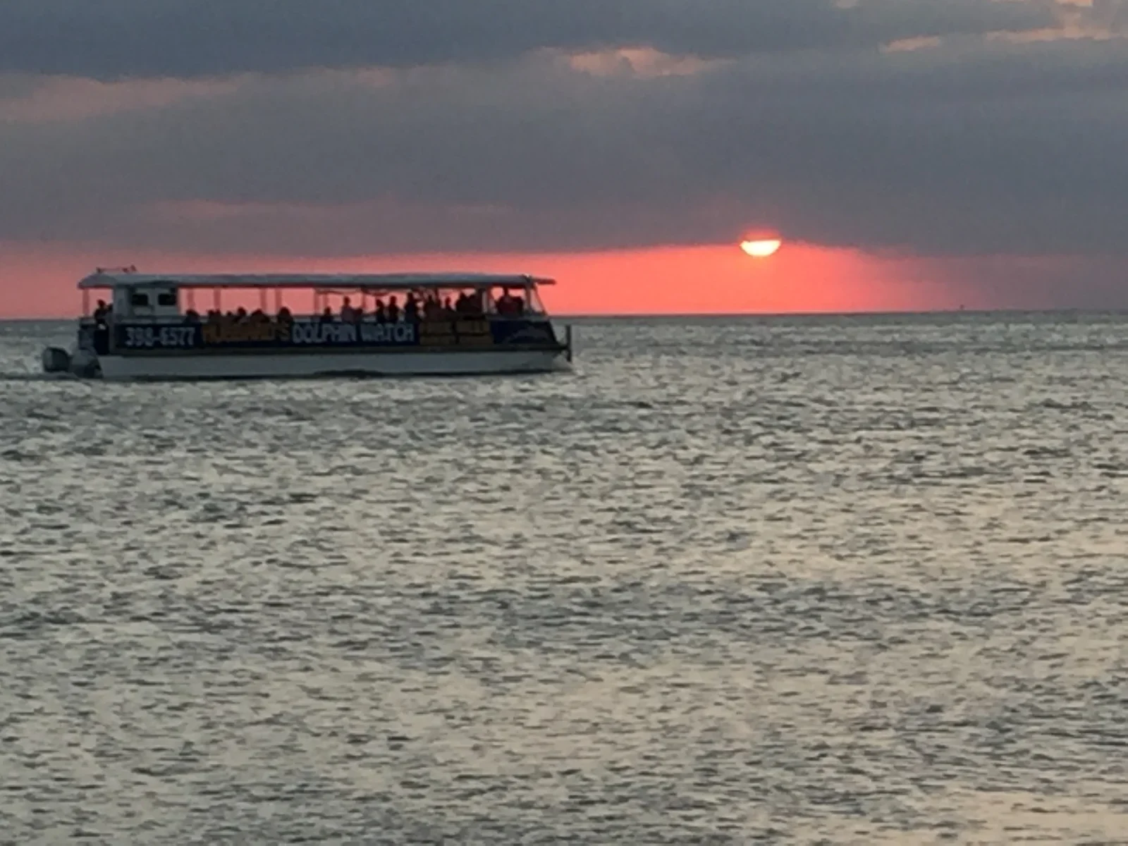 Sunset dolphin cruise boat in St. Pete, FL with passengers watching the sun set over the Gulf of Mexico