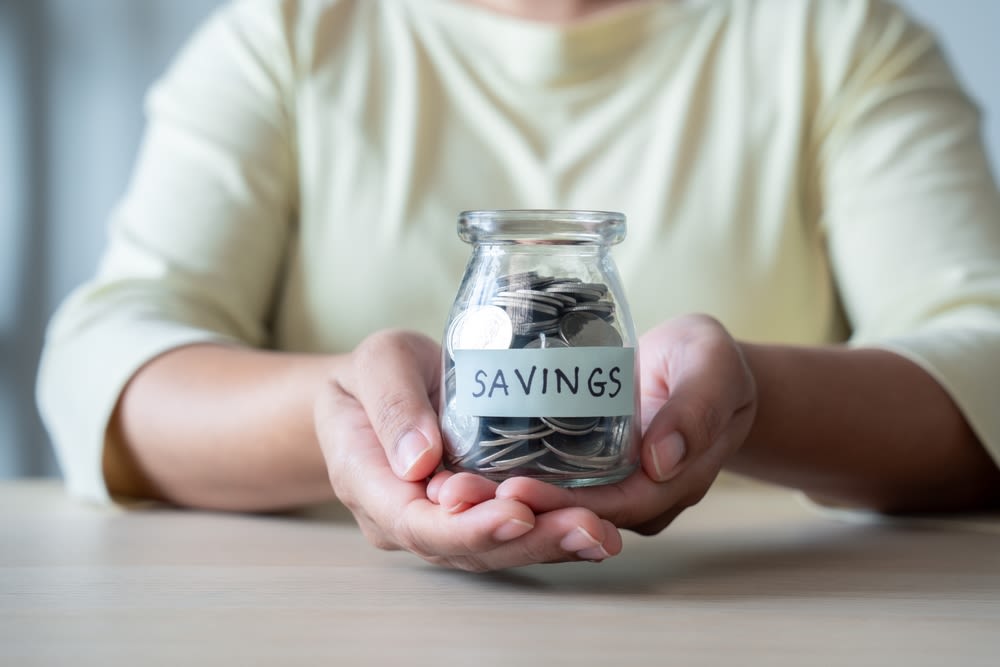 A-person-holding-a-jar-of-savings A person holding a jar of savings