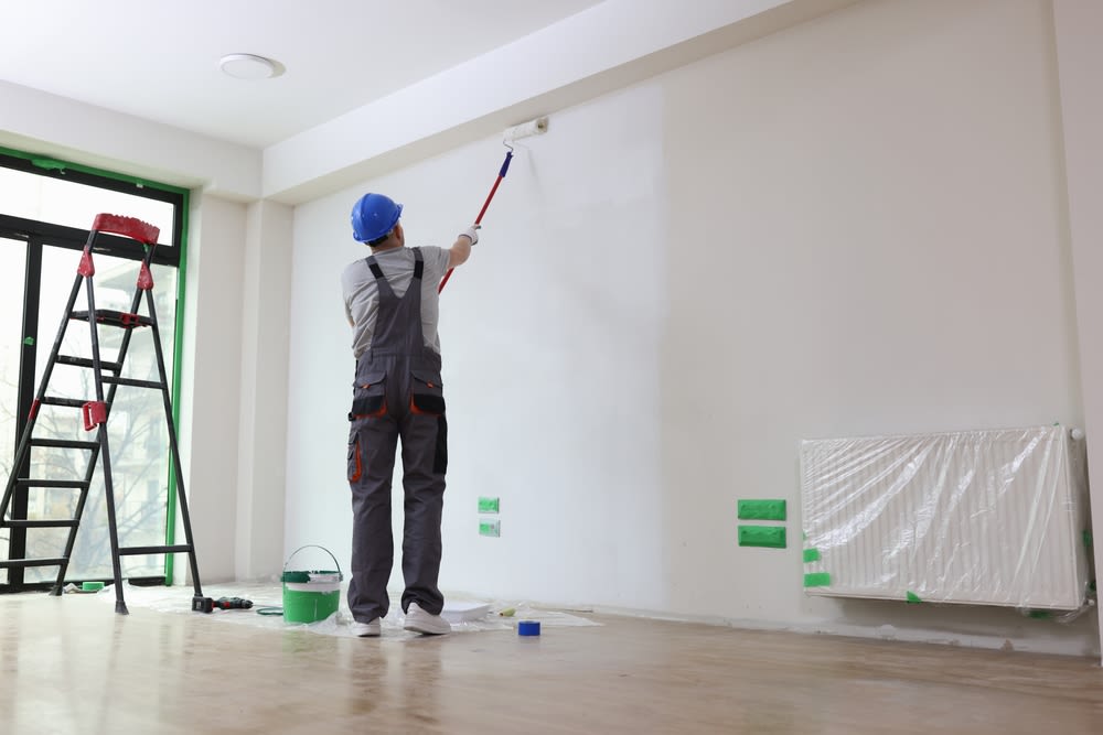 man painting the wall with white paint