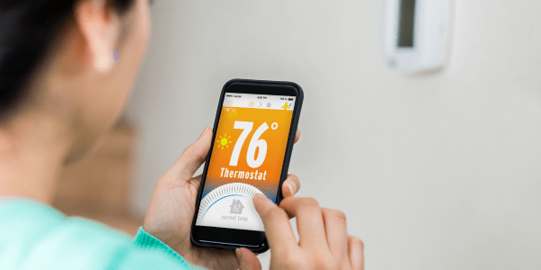 woman adjusting thermostat on her cell phone