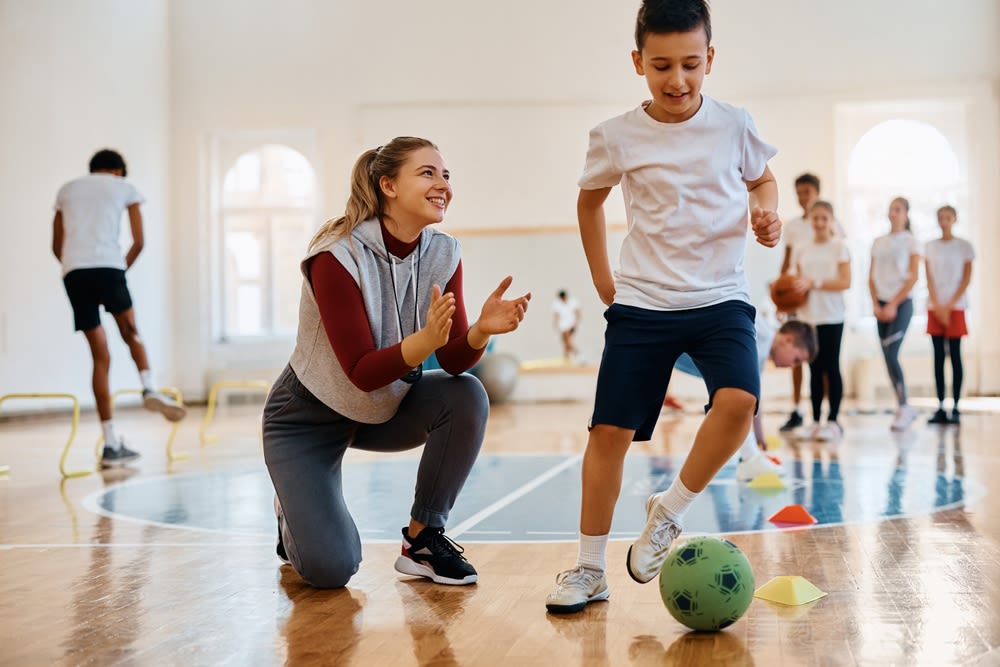 Kid-kicking-a-ball-with-teacher Kid kicking a ball with teacher