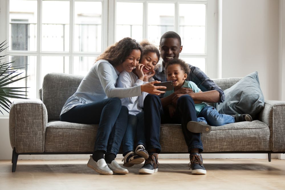 a-family-sitting-on-the-couch-watching-a-virtual-tour-on-the-phone a family sitting on the couch watching a virtual tour on the phone
