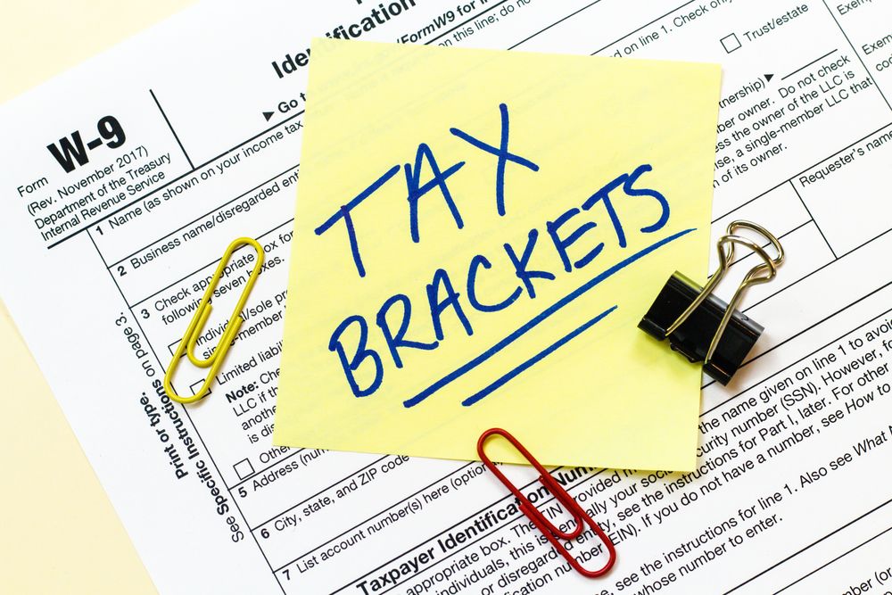 Tax-forms-and-Tax-Brackets-written-on-sticky-notes Tax forms and Tax Brackets written on sticky notes