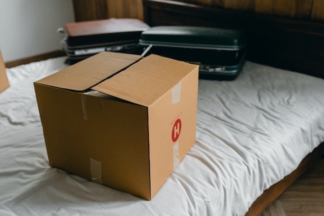 It’s easier to pack for moving day when you don’t have much clutter Packed box and two suitcases on a bed