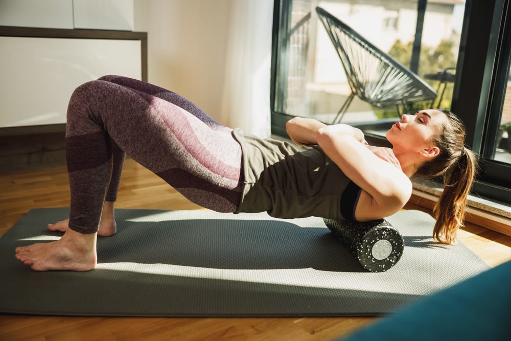 A-woman-doing-stretching-and-foam rolling A woman doing stretching and foam rolling