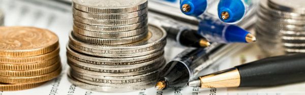 Money, coins and a pen on top of a book