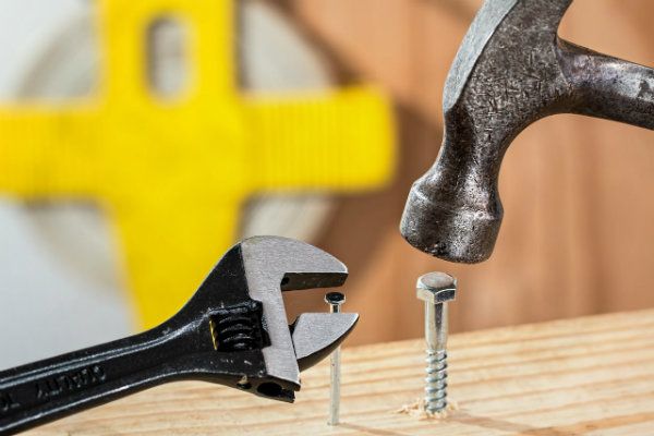 Using A hammer and a wrench to work on a board of wood