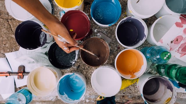 Multiple paint cans laid out on a wooden floor