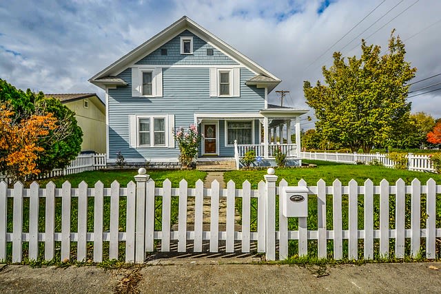 Big blue house with yard and white picket fence