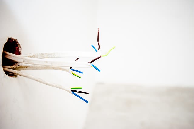Broken cables coming out of a missing outlet in the wall