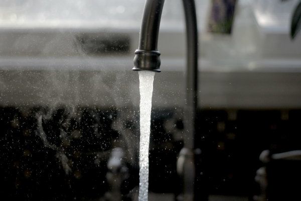 Running faucet in a kitchen steaming from hot water