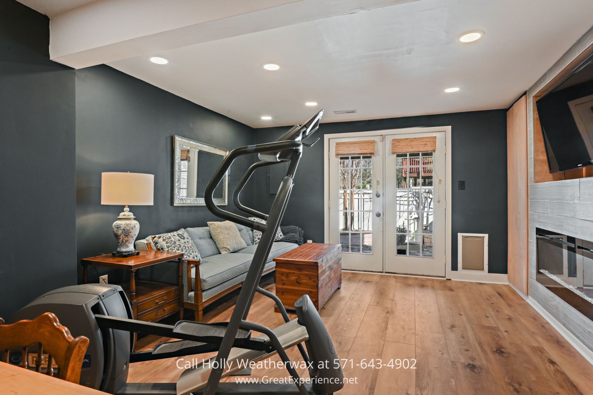 Reston VA Home - Cozy family room with built-in desk and electric fireplace in updated 2-bedroom townhome, Reston VA. a family room filled with furniture and a flat screen tv