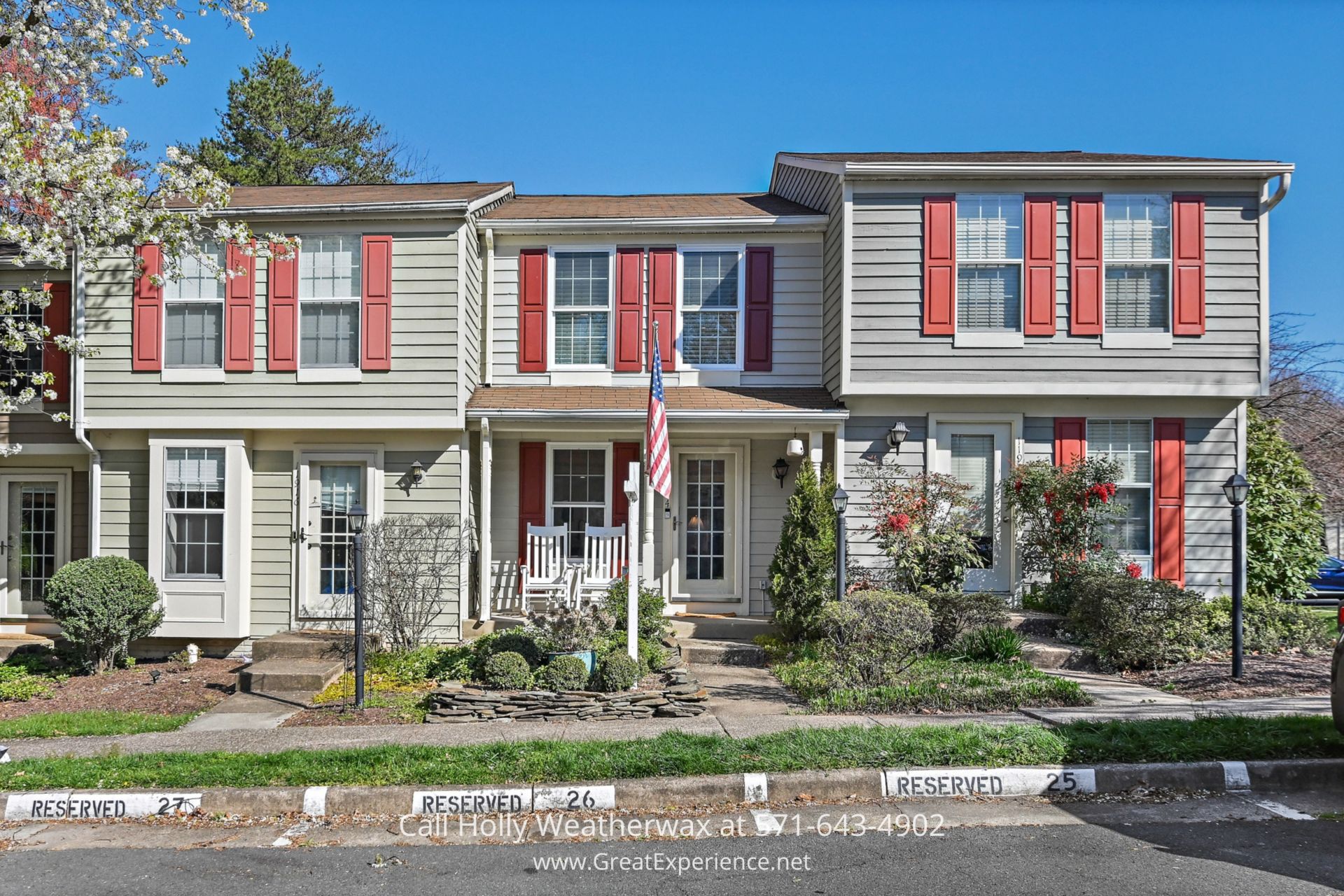 Home for Sale in Reston VA - Elegant front view of 11914 Fieldthorn Ct, a Reston townhome, situated in a peaceful cul-de-sac within the Thornhill Cluster, showcasing its charming architecture and welcoming front porch. a two story house with red shutters and a flag