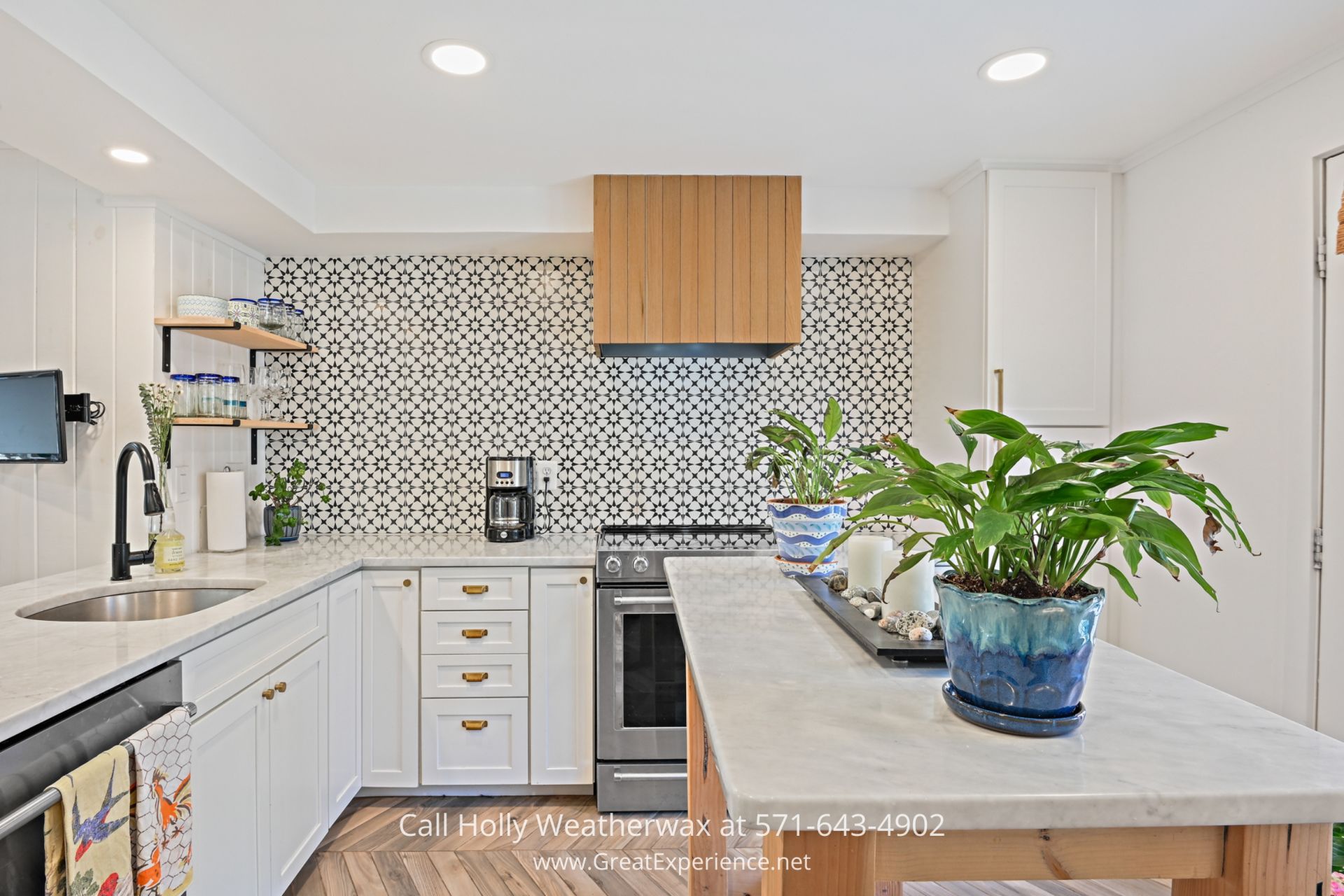 Reston VA Townhome - Modern and updated kitchen in a Reston townhouse with ample storage, stainless appliances including a built-in range, and open shelving, leading to a charming deck. a kitchen with a sink, stove, and a potted plant