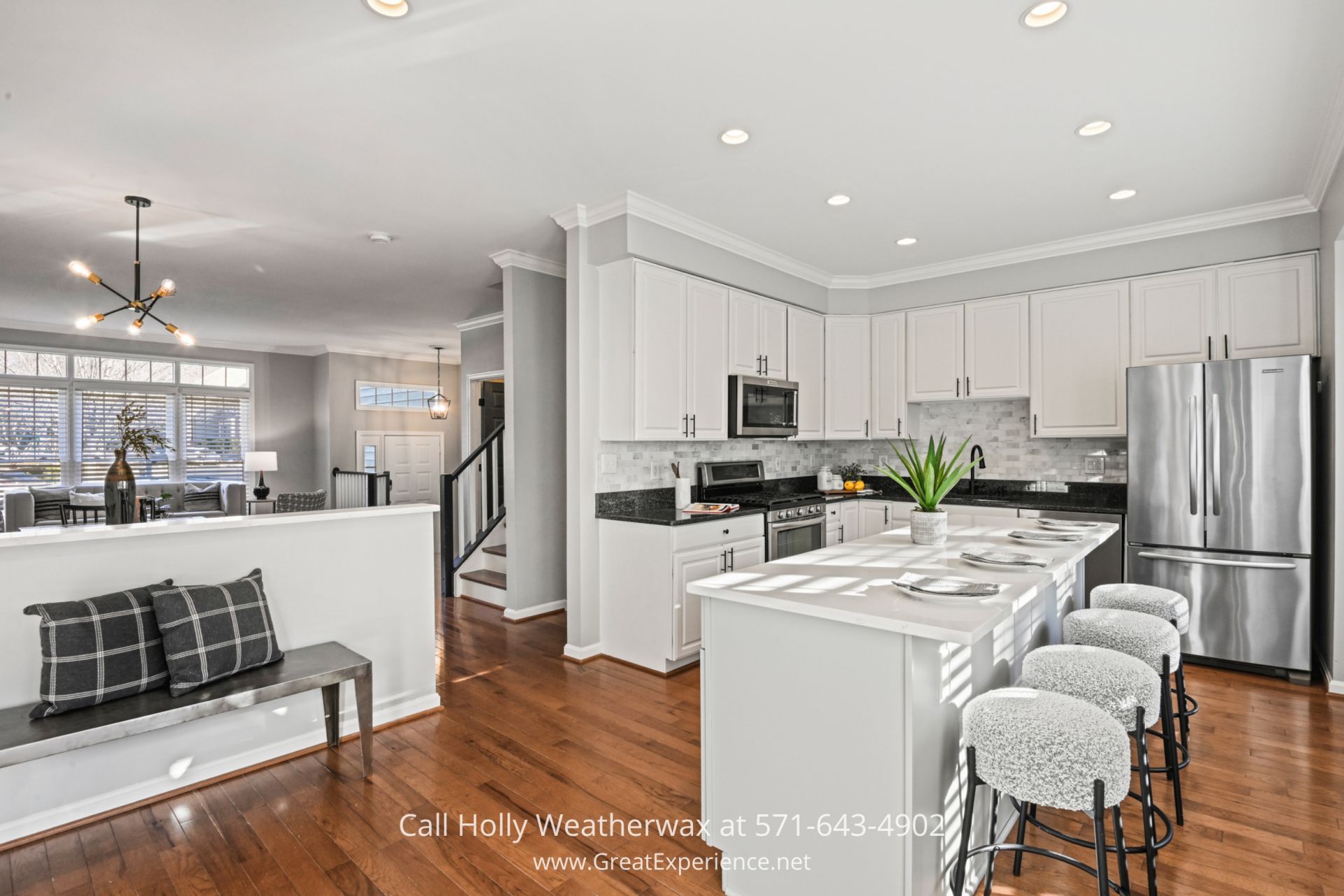Contemporary Kitchen in Reston VA Townhouse A modern white kitchen with stainless steel appliances, quartz countertops, a large island with barstool seating, and pendant lighting, perfect for cooking and entertaining.