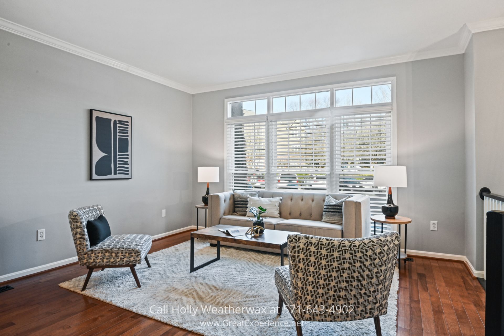 Elegant Living Room in Reston VA Townhouse A spacious living room with a large front window, a neutral gray couch, stylish patterned chairs, and contemporary artwork, creating a cozy and elegant space.