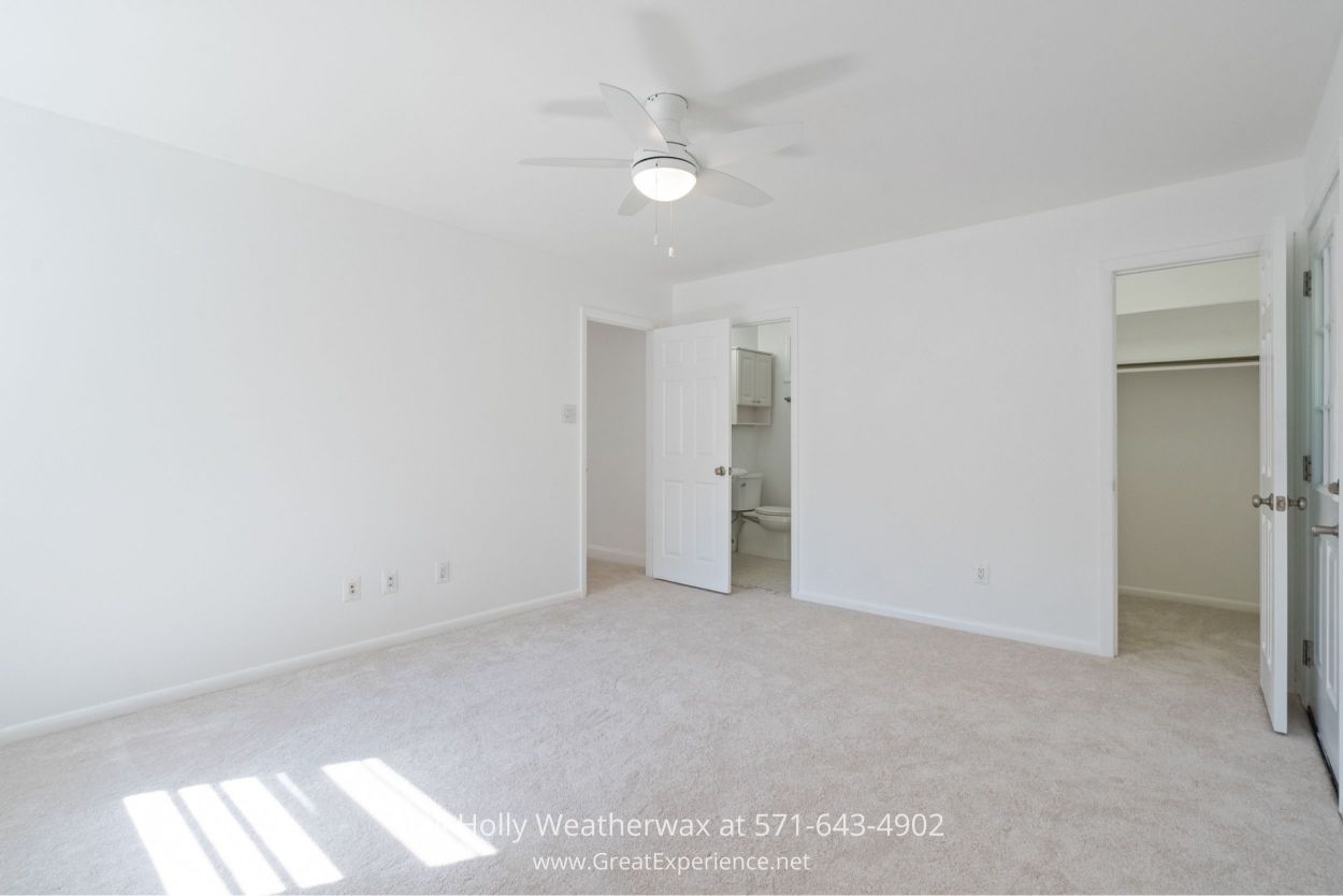 Spacious primary bedroom with ceiling fan, and direct access to an en-suite bathroom in this Chantilly VA home for sale.