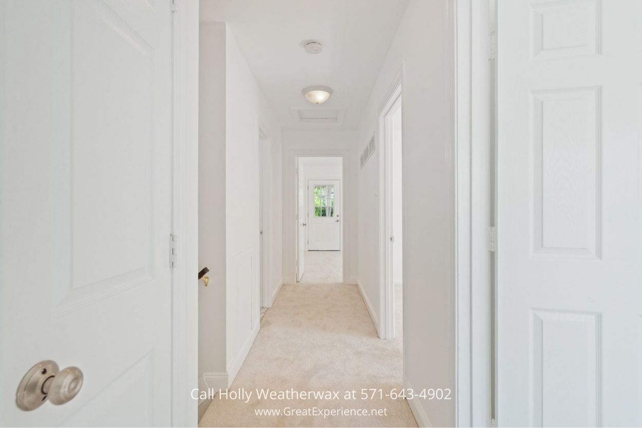 Bright hallway with white walls, neutral carpet, and natural light connecting rooms in this Chantilly VA home for sale.