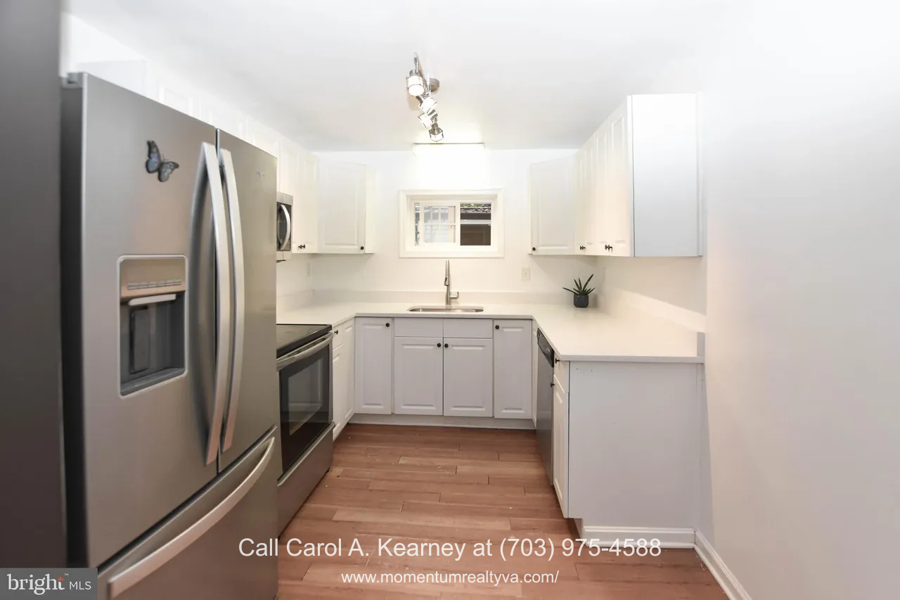 420 White Oak Ln 17 Bright updated kitchen inside the 420 White Oak Ln, Bluemont, VA home for sale, featuring white cabinetry, stainless steel appliances, modern lighting, a single window above the sink, and warm wood flooring.