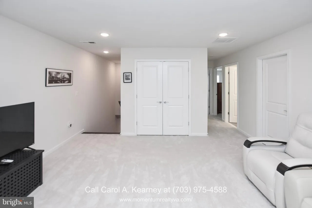 19873 Silvery Blue Ter, Ashburn, VA 20147 Finished lower-level family room at 19873 Silvery Blue Ter in Ashburn, VA, featuring plush carpeting, recessed lighting, neutral walls, and a spacious open layout ideal for flexible living in the Lexington 7 55+ community.