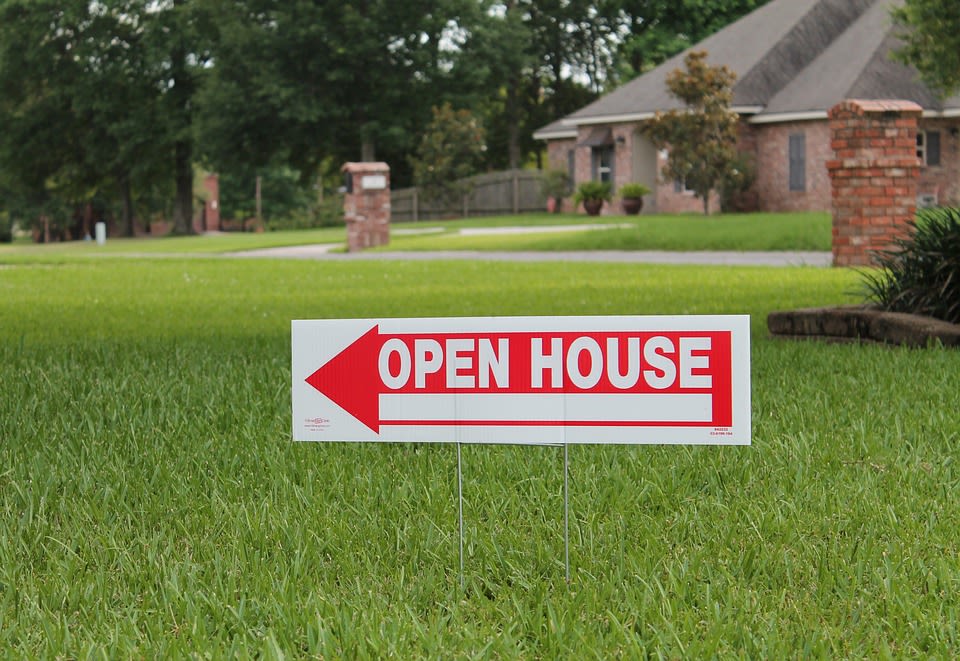 AN open House sign on the front lawn of a house