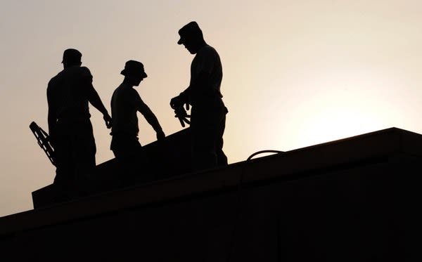 A group of construction workers working on the roof of a home