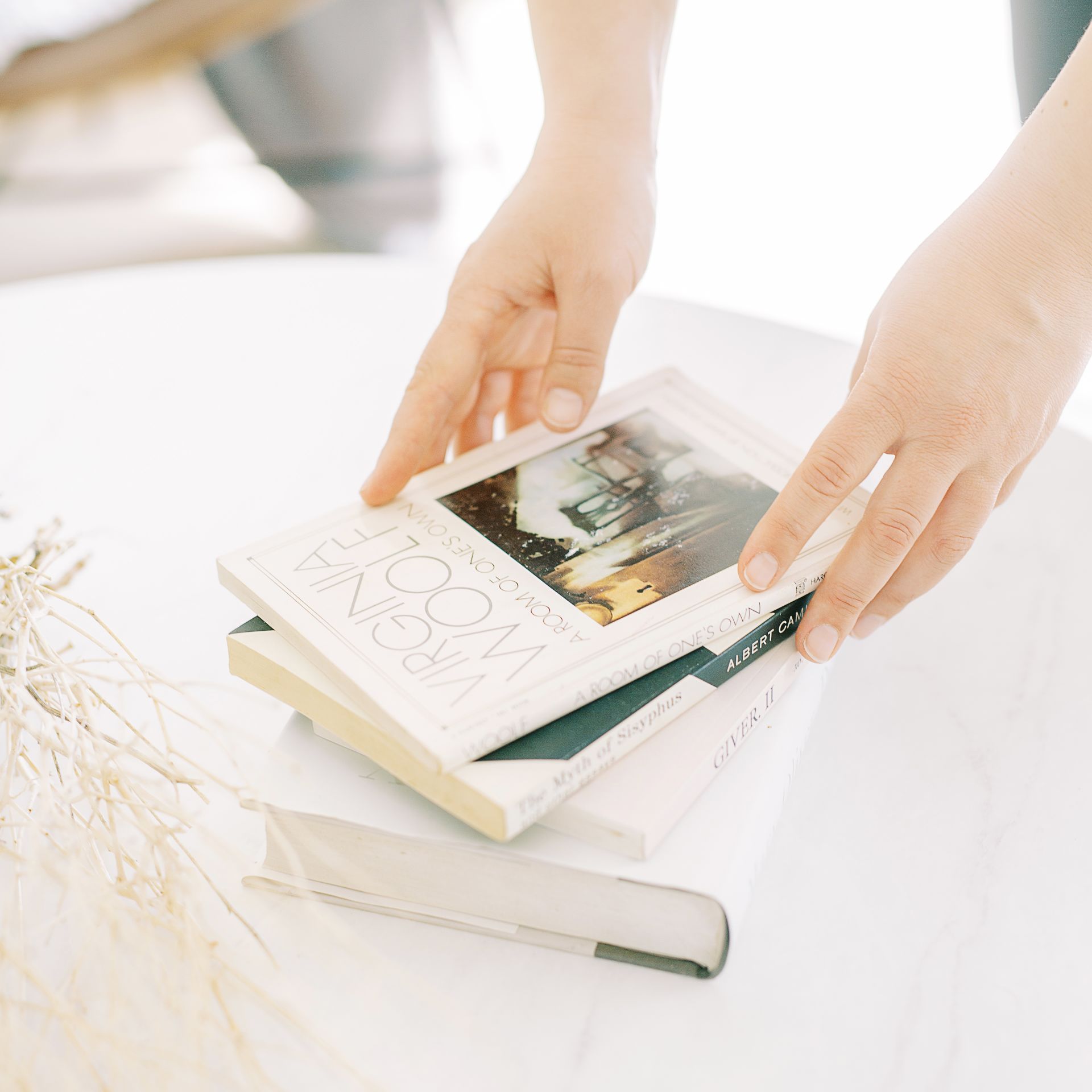 a room of one's own woman placing virginia wolfe's book a room of one's own, on a sunlit table