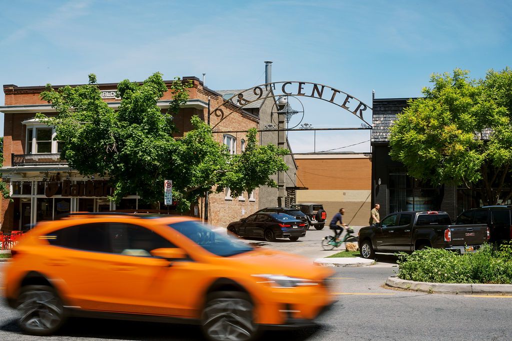 an orange car speeds past the metal 9th & 9th sign in salt lake city