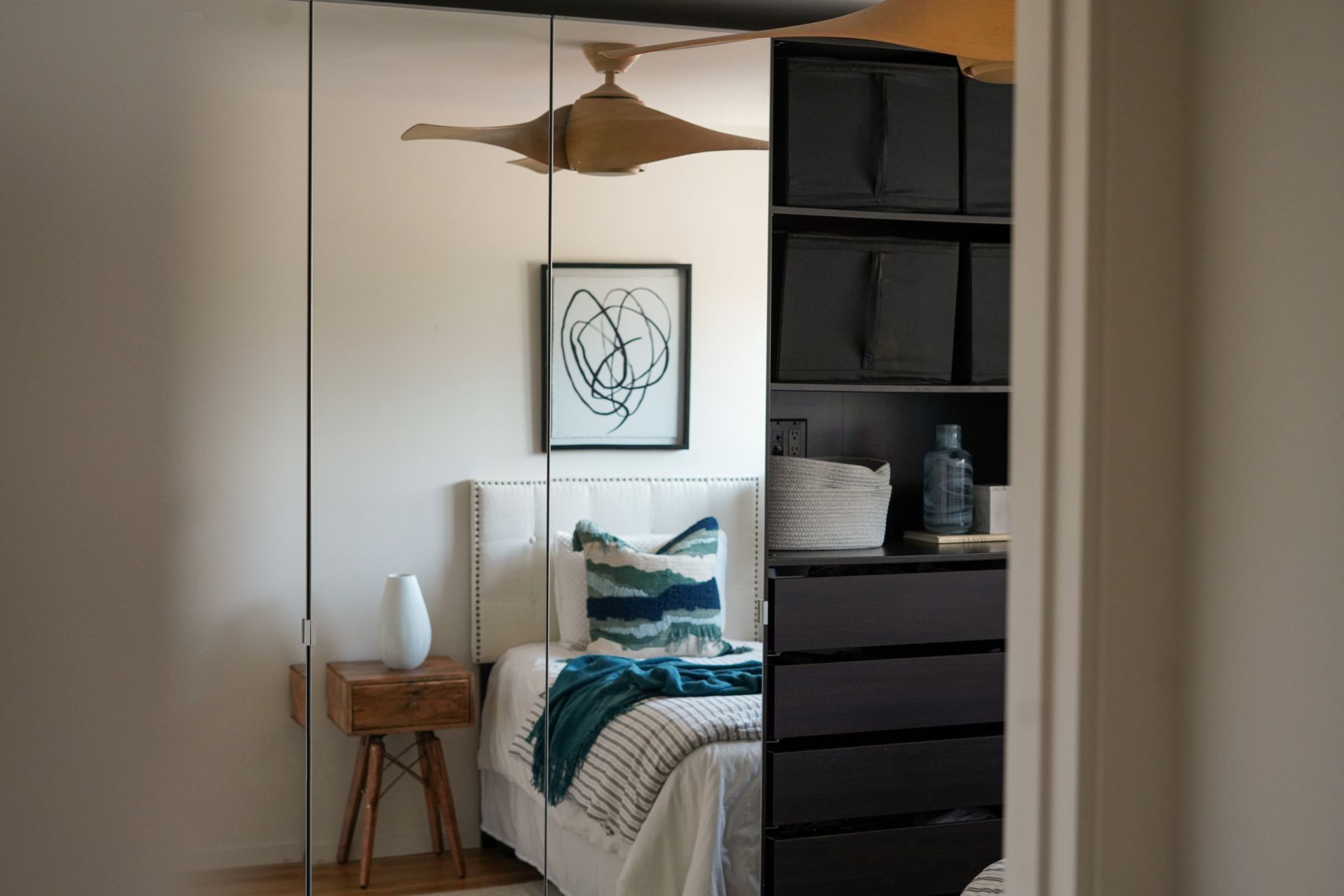 a modern bedroom in blue and white pictured behind a black bookcase