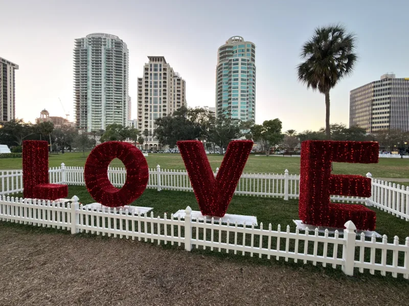 Red LOVE sculpture in a downtown St. Petersburg park with the St. Pete skyline behind it near Beach Drive