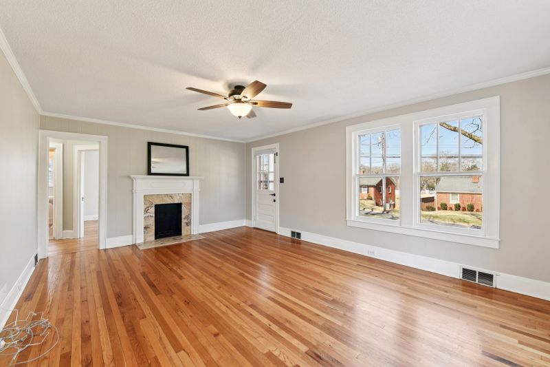 Light-filled living room with refinished oak floors and travertine fireplace in renovated Concord North Carolina bungalow.