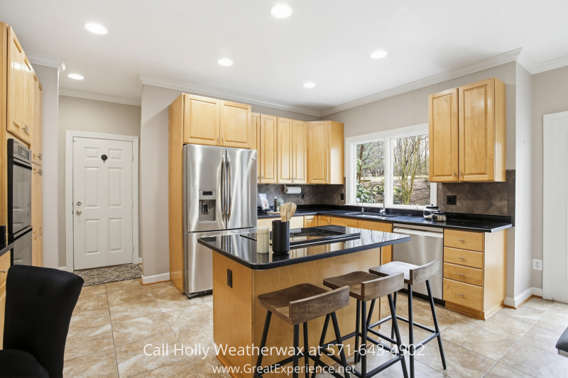 Spacious kitchen at 11316 Bright Pond Lane, Reston, VA featuring a center island with seating, stainless steel appliances, ample cabinetry, and bright windows overlooking the yard.
