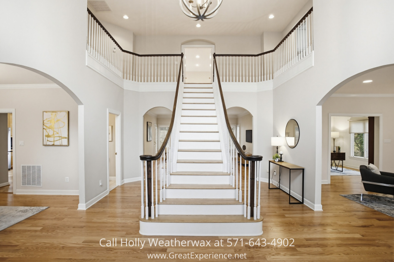 Two-story foyer at 11316 Bright Pond Lane, Reston, VA, featuring a grand curved staircase, hardwood floors, and open, light-filled entryway.