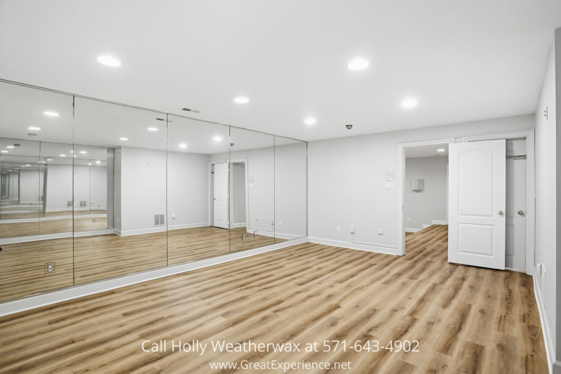 Finished lower-level recreation room at 11316 Bright Pond Lane, Reston, VA featuring wood-look flooring, recessed lighting, and a full mirrored wall ideal for a home gym or studio.