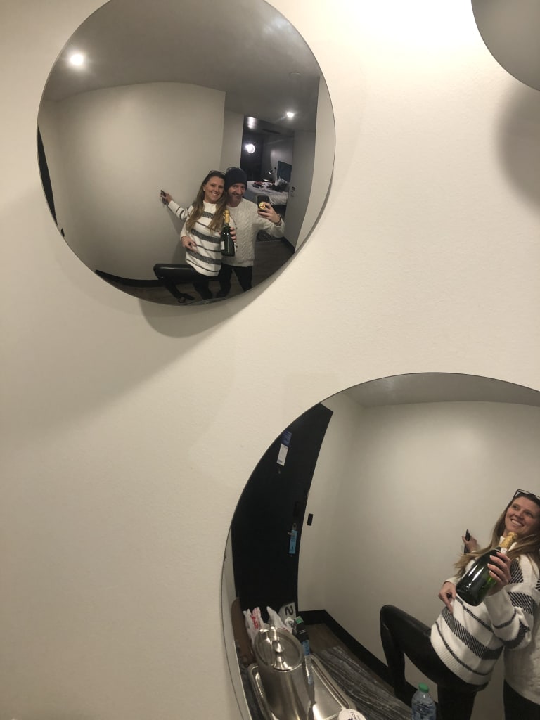 Creative shot of Sean and Steavy reflected in round mirrors holding a champagne bottle — artistic branding concept.