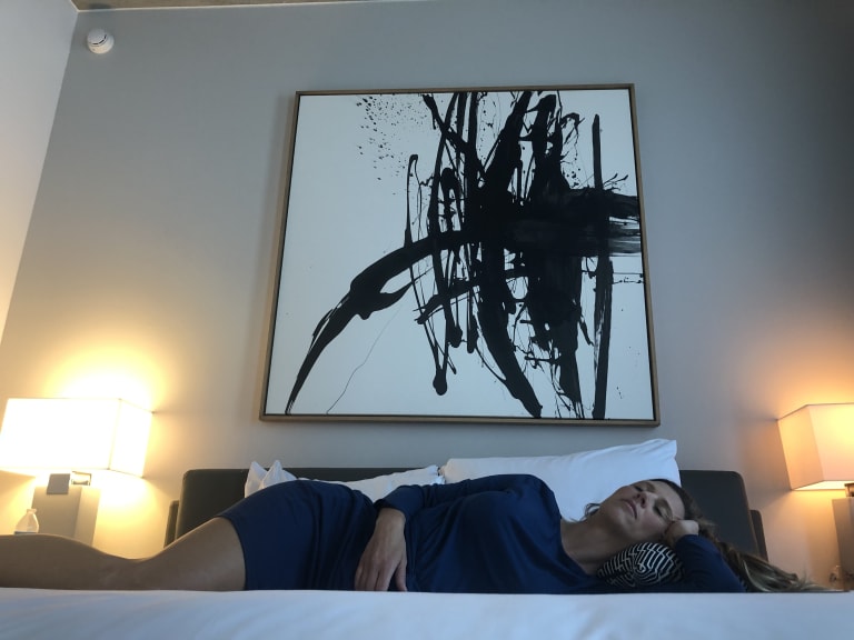 Steavy Carter laying back on a hotel bed at the Pittman Hotel — relaxed and modern branding with boutique vibes.