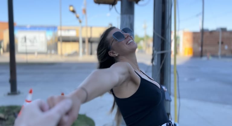 Steavy Carter twirling in Deep Ellum with big sunglasses and a black top, capturing movement and energy in her real estate branding.