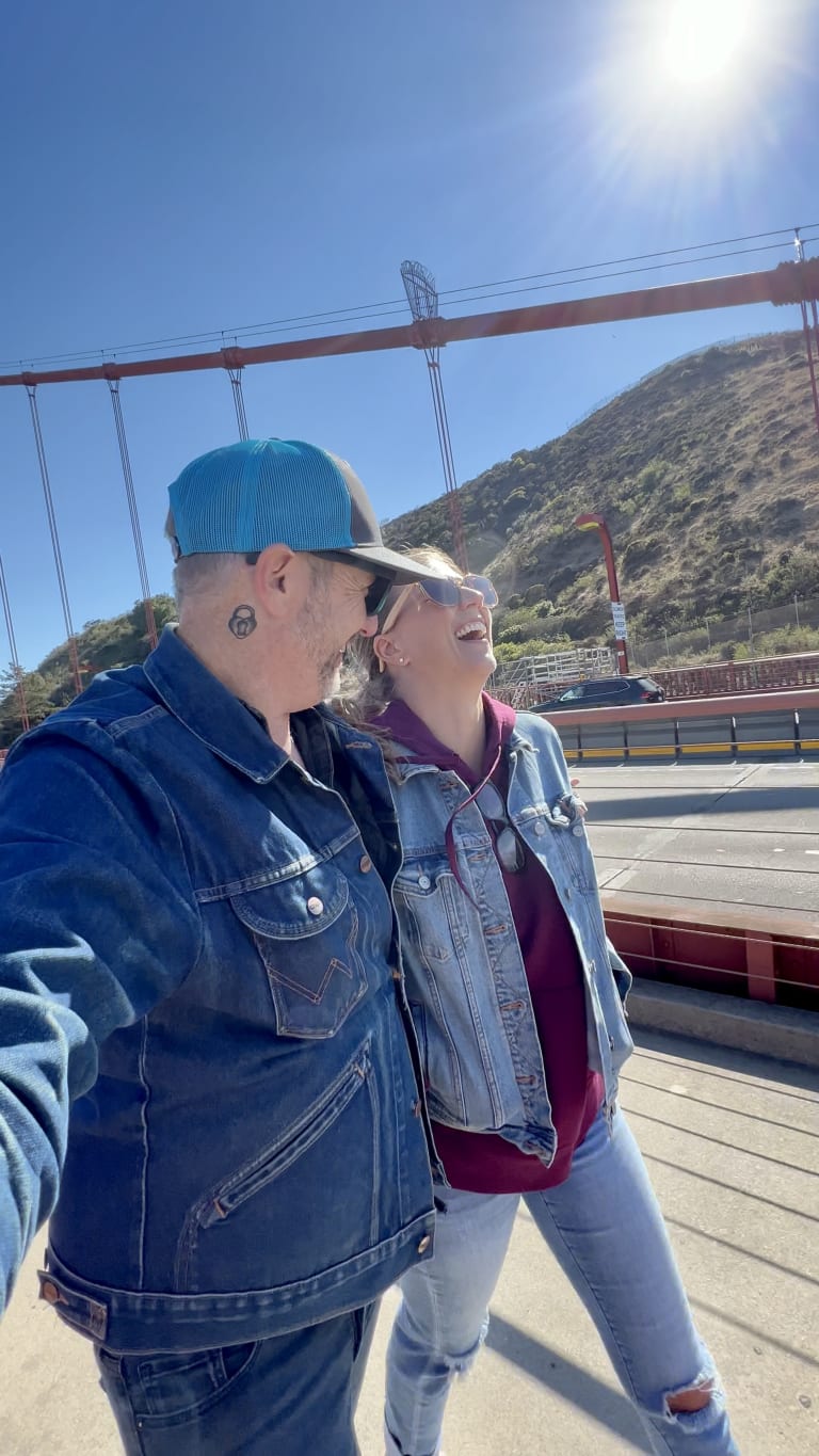 Sean looking at Steavy as she laughs on the Golden Gate Bridge — warm and romantic team photo.