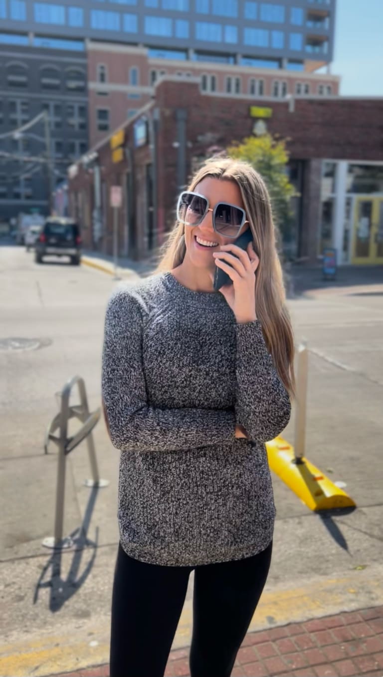 Steavy Carter on a phone call in a gray sweater, smiling and laughing — approachable and smart brand vibe.