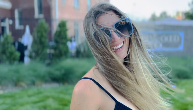 Steavy Carter mid-laugh with her hair blowing in the breeze — candid outdoor branding photo full of joy and spontaneity.
