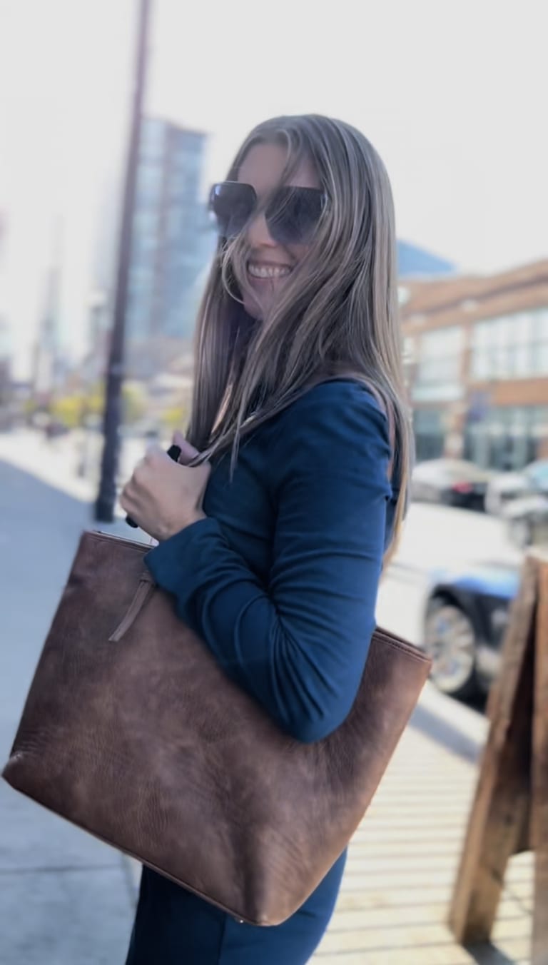Steavy Carter smiling wide in a blue dress, walking down the street with blonde hair — fresh and friendly brand image.