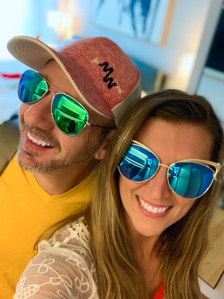 Steavy Carter in cat-eye sunglasses smiling beside Sean — lighthearted couple selfie.