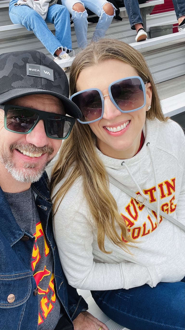 Sean and Steavy Carter in Austin College sweatshirts and big sunglasses, seated in the bleachers — college pride meets style.