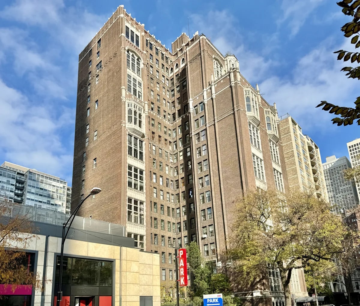 Red brick Tudor Revival-style apartment building with stone trim and oriel windows on Cedar Street in the Gold Coast, Chicago