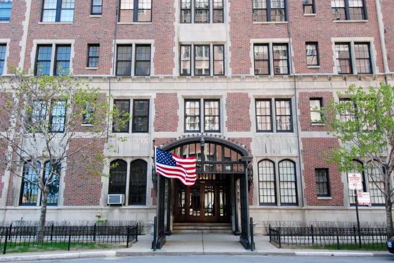 Arched entrance with an American flag on a vintage brick and limestone high-rise on N Lake Shore Drive in the Gold Coast, Chicago