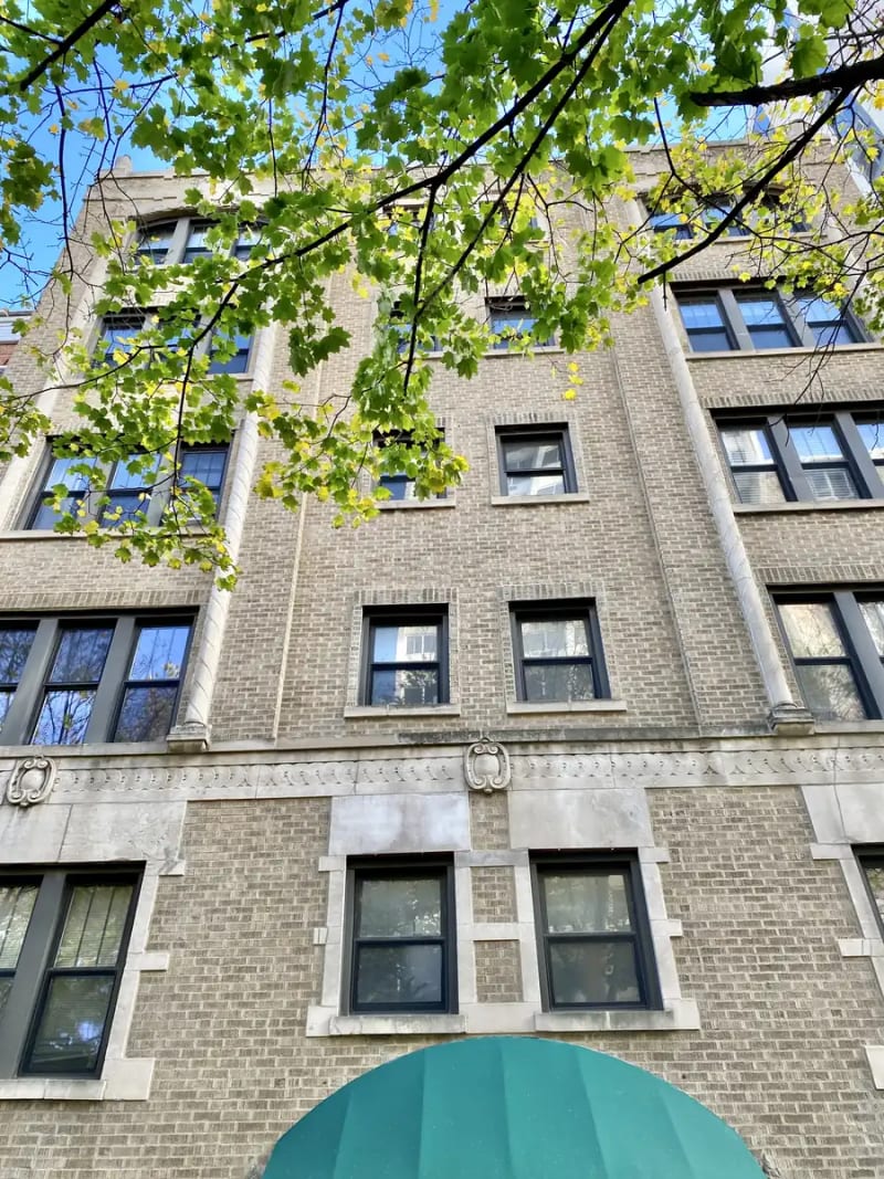 Vintage tan brick building with stone trim and a green entrance awning on Dearborn Street in Chicago's Gold Coast